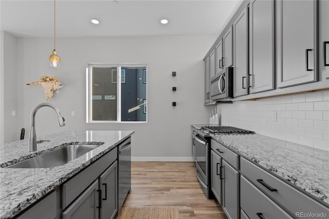 kitchen featuring decorative backsplash, gray cabinets, appliances with stainless steel finishes, and a sink