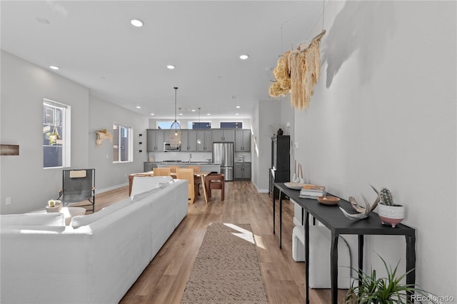 living room featuring recessed lighting, light wood-style floors, and baseboards