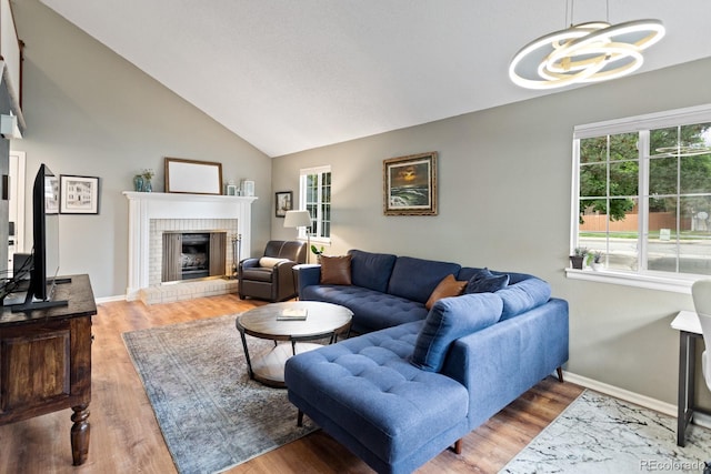 8997 W 88th Ave, Westminster, CO 80021 - living room featuring a chandelier, healthy amount of natural light, a fireplace, vaulted ceiling, and wood finished floors