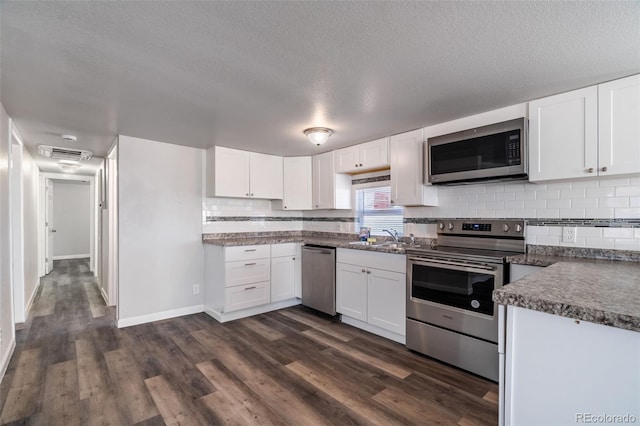 530 Illinois St, Penrose, CO 81240 - kitchen with appliances with stainless steel finishes, dark hardwood / wood-style floors, white cabinetry, sink, and decorative backsplash