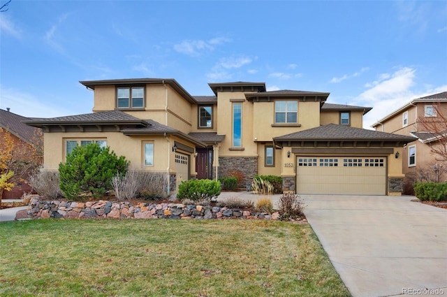 prairie-style home with a garage and a front lawn