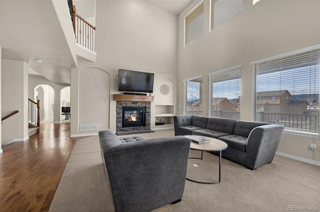 living room with hardwood / wood-style floors, built in shelves, a fireplace, and a high ceiling