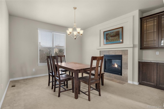 dining area featuring a fireplace, light carpet, and an inviting chandelier