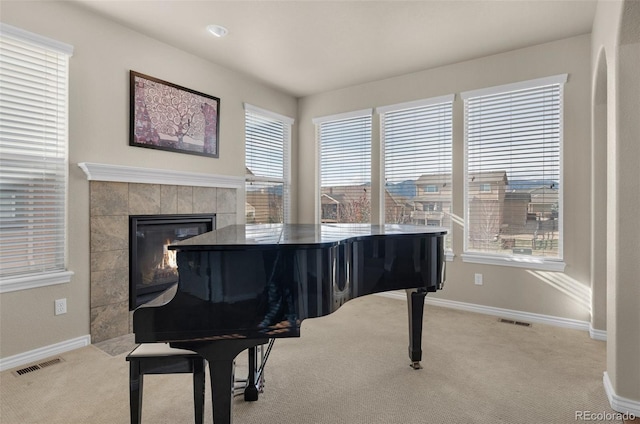 misc room with light carpet and a tiled fireplace