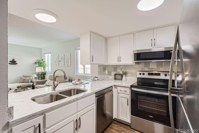 8993 W 88th Pl, Westminster, CO 80021 - kitchen featuring appliances with stainless steel finishes, wood finished floors, light stone counters, and white cabinetry