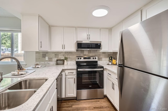 8993 W 88th Pl, Westminster, CO 80021 - kitchen with appliances with stainless steel finishes, wood finished floors, white cabinetry, light stone countertops, and decorative backsplash