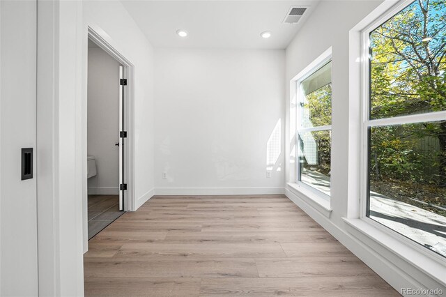 corridor featuring a wealth of natural light and light wood-type flooring