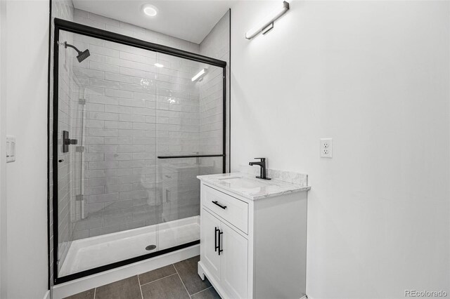 bathroom with tile patterned flooring, vanity, and a shower with door