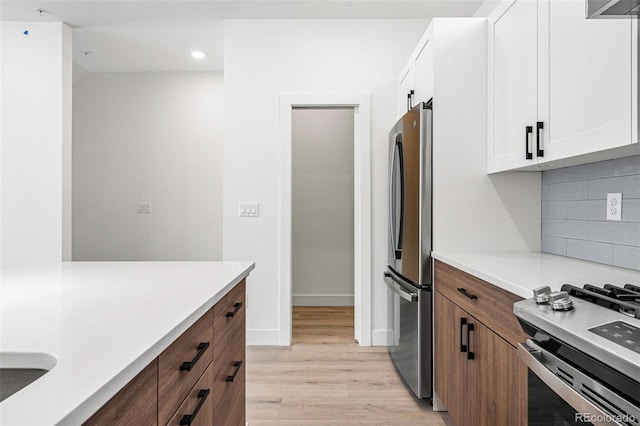 kitchen with white cabinets, light wood-type flooring, stainless steel appliances, and decorative backsplash