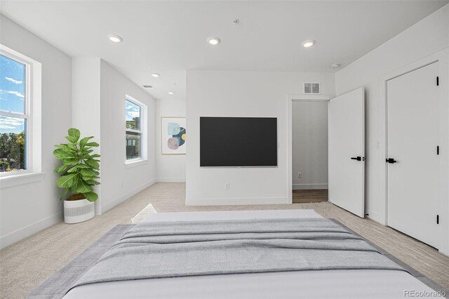 bedroom featuring light colored carpet and multiple windows