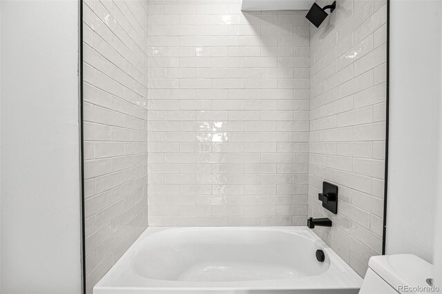 bathroom featuring toilet and tiled shower / bath combo