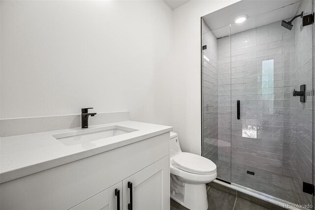 bathroom featuring a shower with door, vanity, toilet, and tile patterned flooring