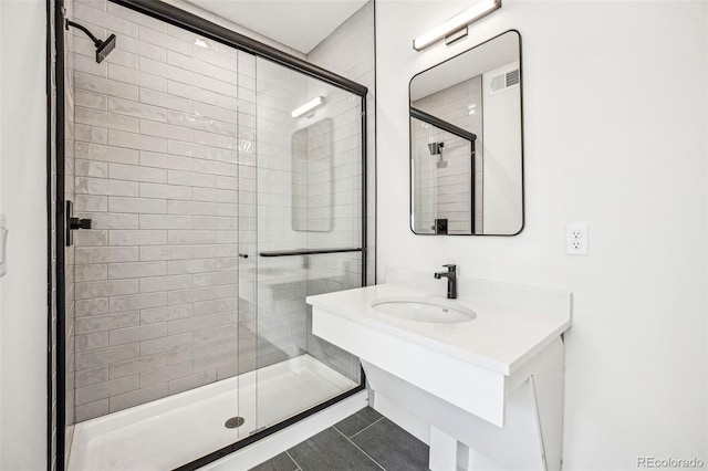 bathroom featuring visible vents, a sink, a shower stall, and tile patterned floors