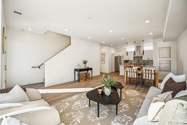 living area with light wood-style flooring, stairway, baseboards, and recessed lighting