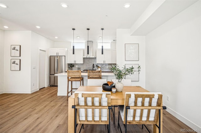 dining room with recessed lighting, light wood-style flooring, and baseboards