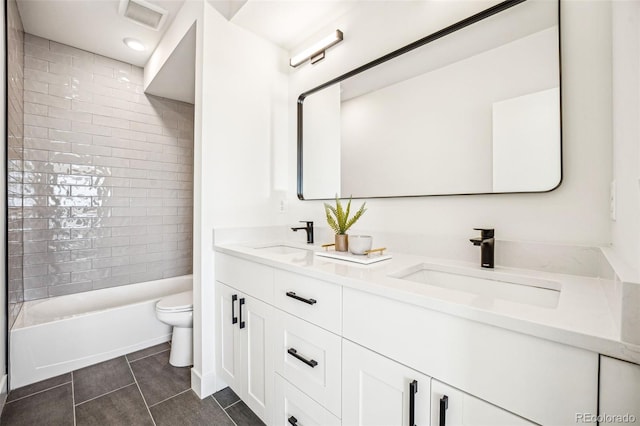 full bath featuring toilet, double vanity, visible vents, and a sink