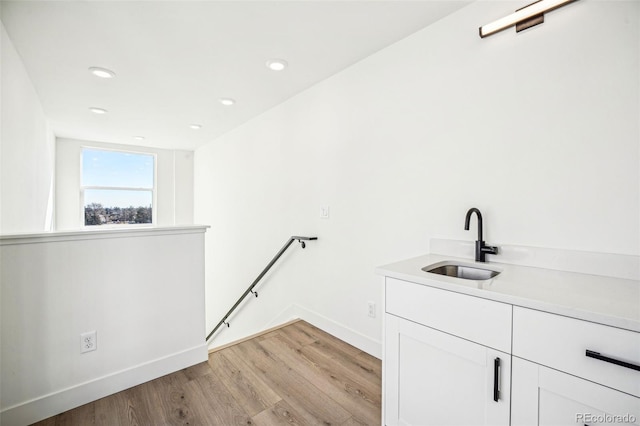 clothes washing area featuring recessed lighting, laundry area, a sink, baseboards, and light wood-type flooring