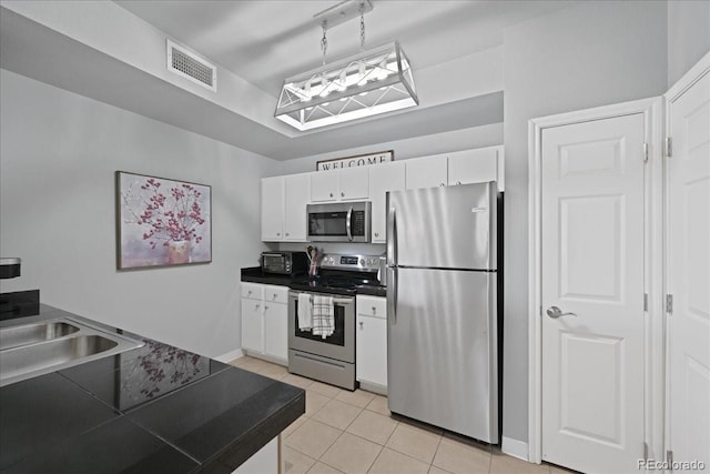 kitchen featuring appliances with stainless steel finishes, sink, white cabinets, hanging light fixtures, and light tile patterned floors