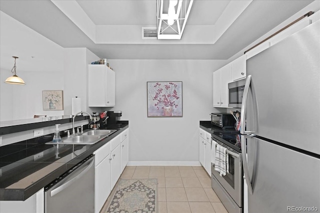 kitchen featuring light tile patterned flooring, sink, hanging light fixtures, appliances with stainless steel finishes, and white cabinets