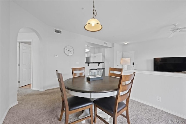 dining space featuring ceiling fan and light colored carpet