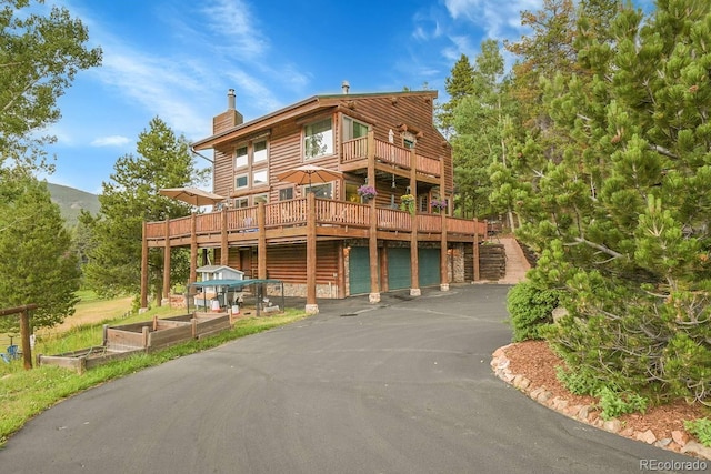 31112 Shadow Mountain Dr, Conifer, CO 80433 - view of front facade with a garage, a chimney, driveway, a garden, and a deck