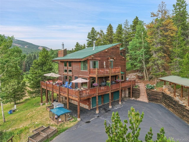 31112 Shadow Mountain Dr, Conifer, CO 80433 - rear view of property with a chimney, a deck, asphalt driveway, a metal roof, and a view of trees