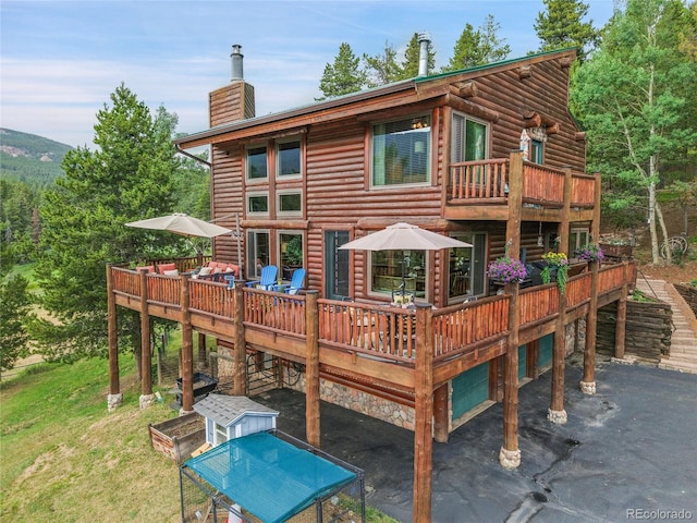 31112 Shadow Mountain Dr, Conifer, CO 80433 - back of property with a chimney, a balcony, and a deck