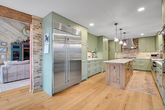 31112 Shadow Mountain Dr, Conifer, CO 80433 - kitchen featuring green cabinets, appliances with stainless steel finishes, wall chimney exhaust hood, light wood-style floors, and recessed lighting