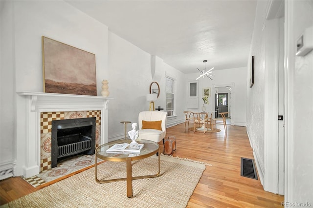 living room with wood-type flooring and a tile fireplace