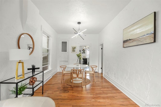 dining space with wood-type flooring, a wealth of natural light, and an inviting chandelier