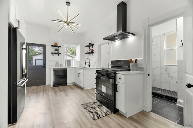 kitchen featuring white cabinets, light hardwood / wood-style flooring, sink, wall chimney range hood, and black appliances