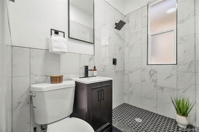 bathroom featuring vanity, toilet, tile walls, and a tile shower