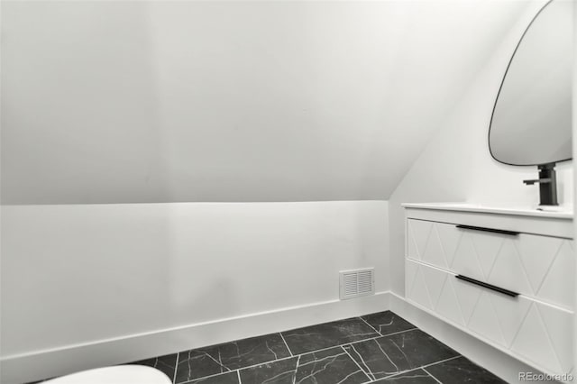 bathroom with vaulted ceiling, toilet, and vanity