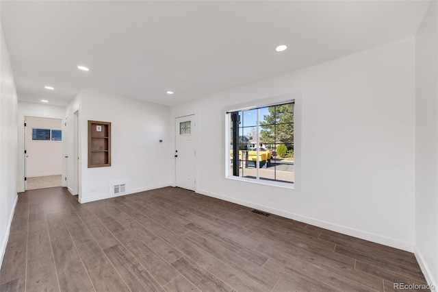 empty room featuring recessed lighting, baseboards, visible vents, and dark wood finished floors