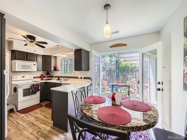 4121 W 111th Cir, Westminster, CO 80031 - kitchen with white appliances, a peninsula, light countertops, light wood-type flooring, and decorative light fixtures