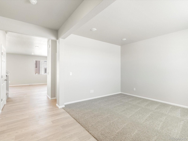 empty room with beamed ceiling and light hardwood / wood-style flooring