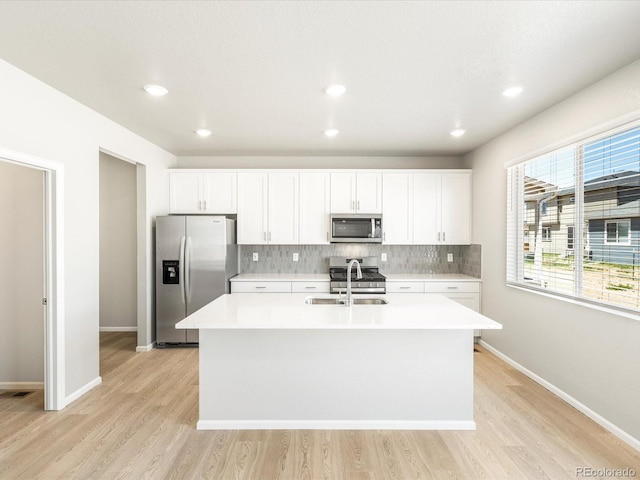 kitchen with sink, white cabinetry, appliances with stainless steel finishes, and an island with sink