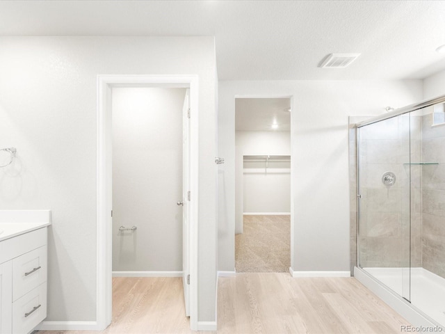 bathroom with vanity, a shower with door, a textured ceiling, and hardwood / wood-style flooring