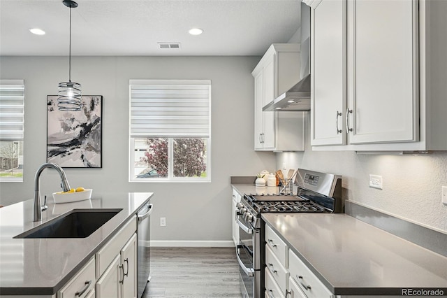 1592 Maggie Mae Ln, Castle Rock, CO 80104 - kitchen with stainless steel appliances, a sink, light wood-type flooring, wall chimney exhaust hood, and recessed lighting
