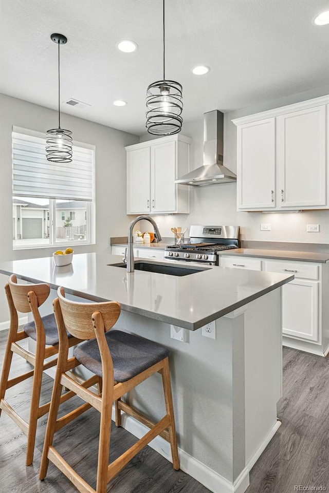 1592 Maggie Mae Ln, Castle Rock, CO 80104 - kitchen with stainless steel gas stove, wall chimney range hood, recessed lighting, wood finished floors, and white cabinetry