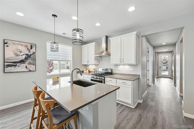 1592 Maggie Mae Ln, Castle Rock, CO 80104 - kitchen with stainless steel gas range, wall chimney exhaust hood, baseboards, a sink, and a kitchen island with sink