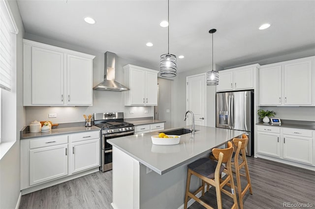 1592 Maggie Mae Ln, Castle Rock, CO 80104 - kitchen with wall chimney exhaust hood, appliances with stainless steel finishes, a sink, wood finished floors, and white cabinetry