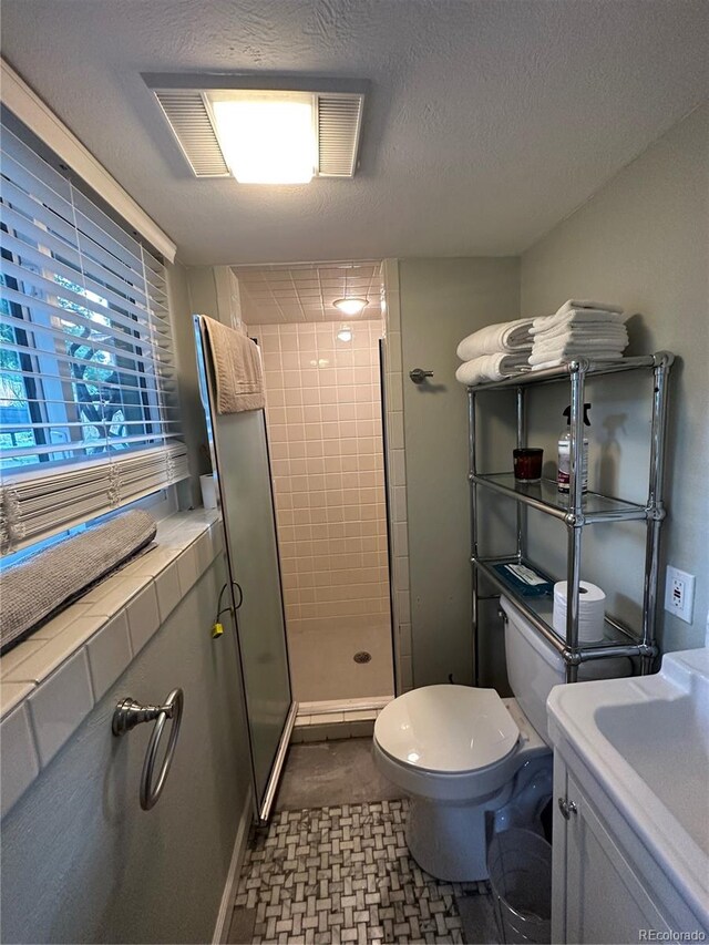 bathroom featuring toilet, an enclosed shower, a textured ceiling, and vanity