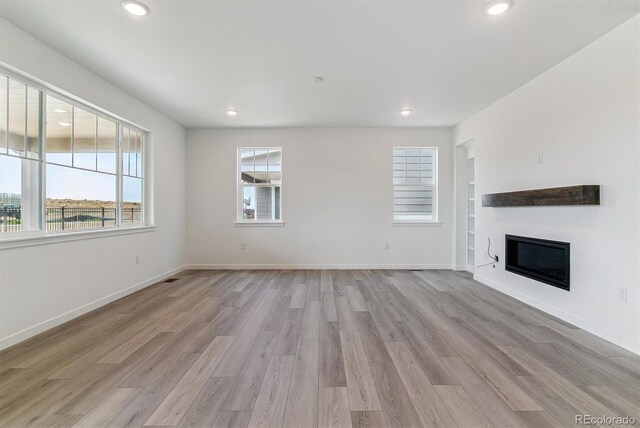 25254 E Warren Pl, Aurora, CO 80018 - unfurnished living room with light wood-style flooring, recessed lighting, a glass covered fireplace, and baseboards
