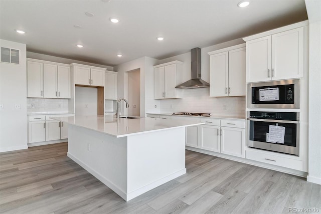 25254 E Warren Pl, Aurora, CO 80018 - kitchen with appliances with stainless steel finishes, wall chimney exhaust hood, a sink, light wood-type flooring, and recessed lighting