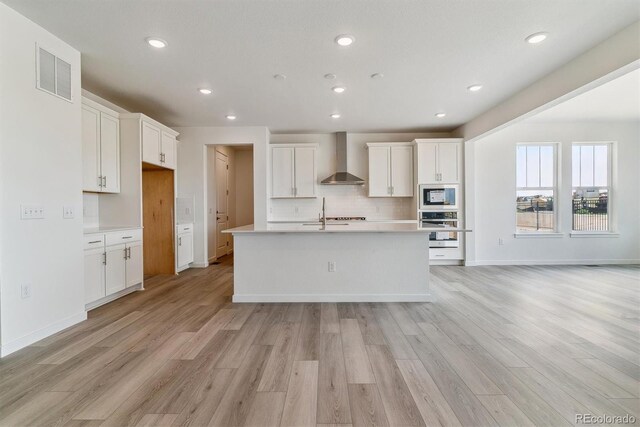 25254 E Warren Pl, Aurora, CO 80018 - kitchen with stainless steel oven, wall chimney range hood, built in microwave, light wood finished floors, and light countertops