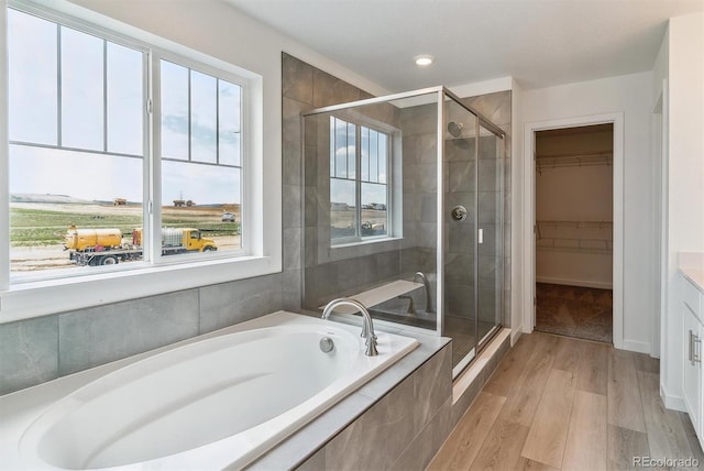 25254 E Warren Pl, Aurora, CO 80018 - bathroom featuring a stall shower, a garden tub, wood finished floors, a walk in closet, and recessed lighting