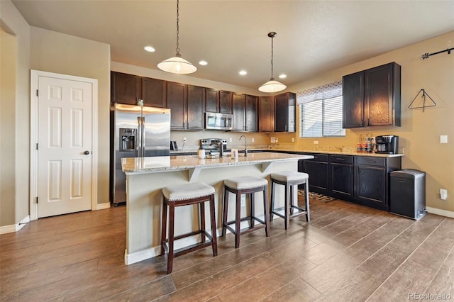 12766 Sunlight Peak Pl, Peyton, CO 80831 - kitchen featuring stainless steel appliances, recessed lighting, dark wood-type flooring, baseboards, and a center island with sink