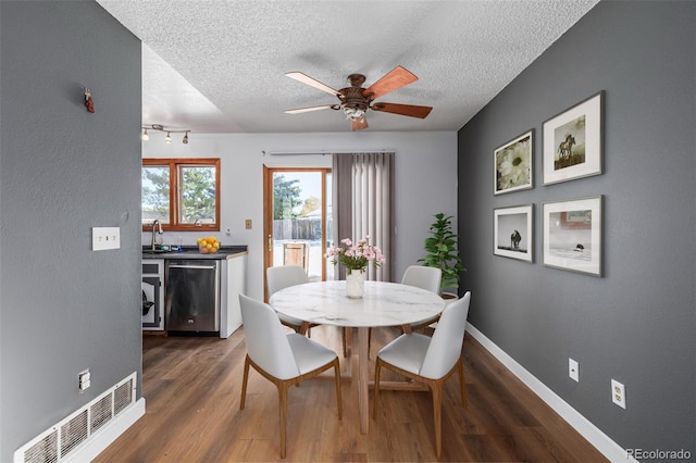 dining room with a textured ceiling, ceiling fan, dark hardwood / wood-style floors, and indoor wet bar