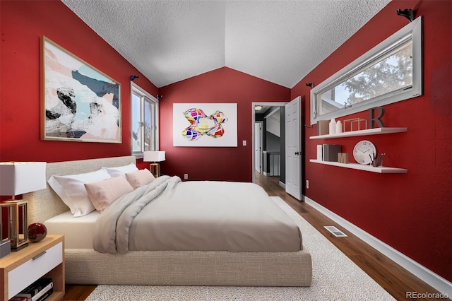 bedroom featuring multiple windows, hardwood / wood-style floors, and vaulted ceiling